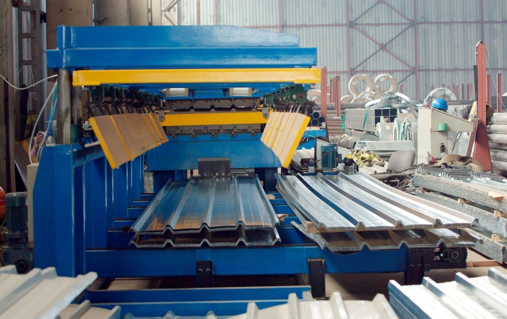 The industrial device for corrugated metal sheets bending by high precision machine in factory. Blue line machine conveyor for cutting sheet metal in mechanical workshop.